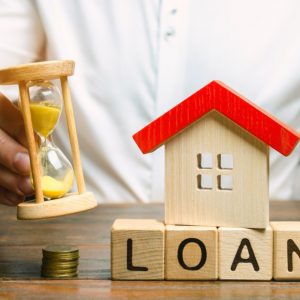 wooden blocks with the word loan miniature house and hourglass in the hands of a businessman the t20 P1rAvR